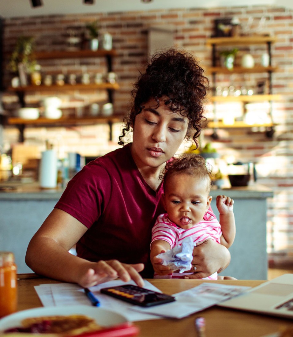 A woman reviewing her bills while holding her child