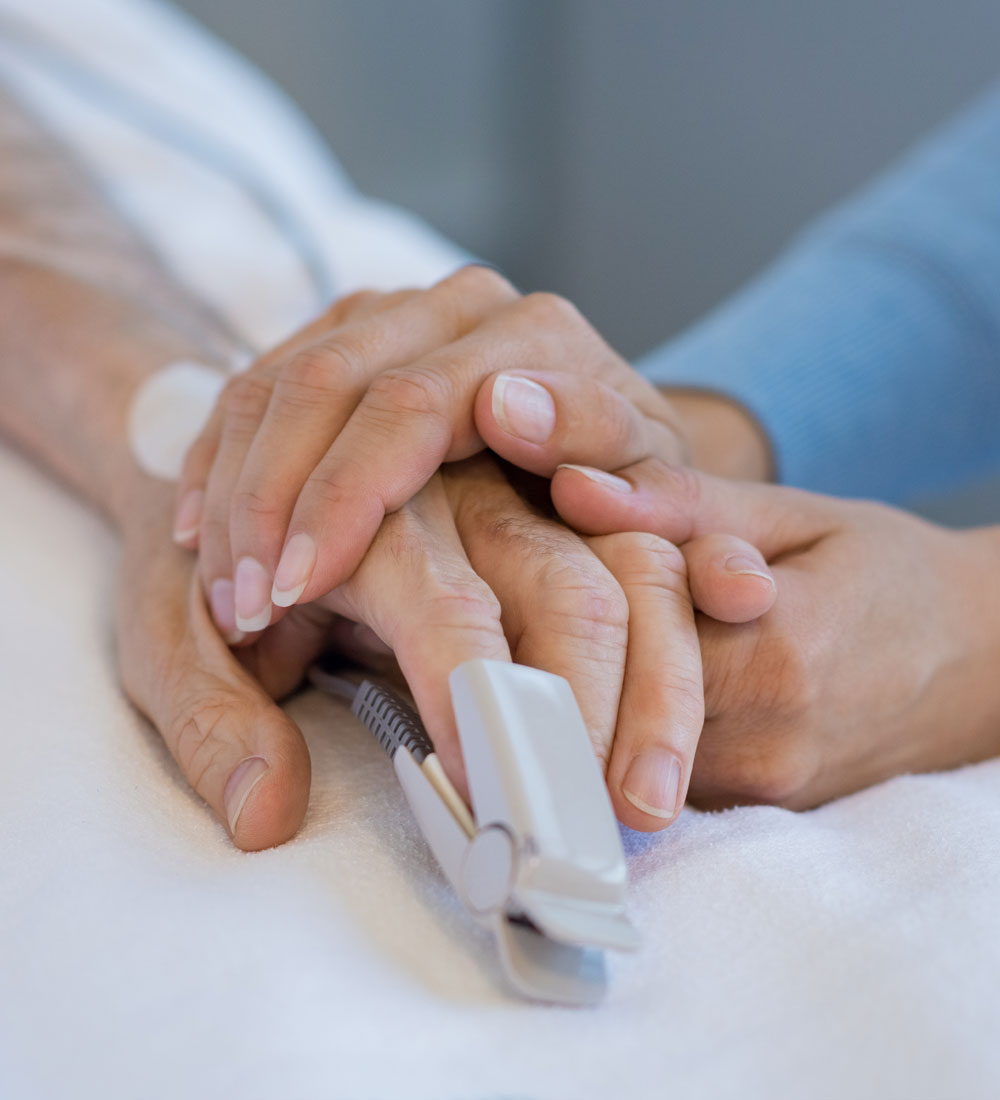 Woman holding the hand of a loved one in the hospital